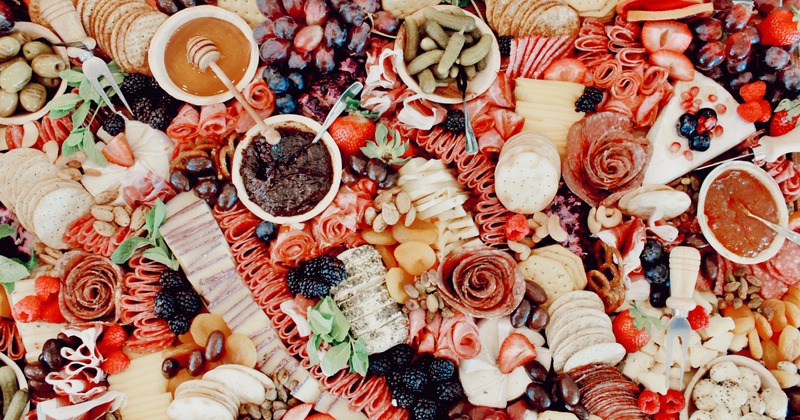 A large charcuterie board with miscellany of foods, overhead view