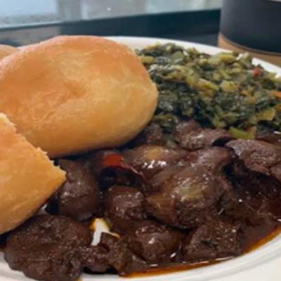 Stewed meat served with fried dumplings, and callaloo.