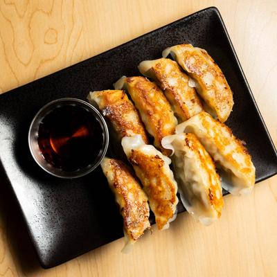 Small plate of pork gyoza with a soy sauce on the side.