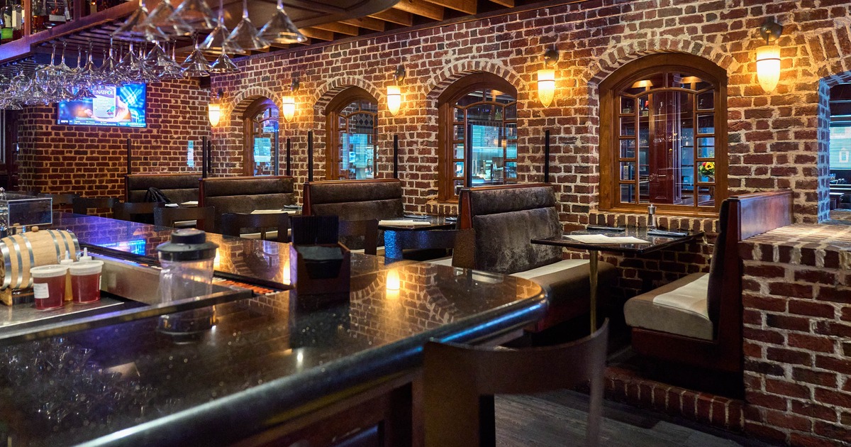 Interior with brick walls, booth seating, a bar and warm lighting.