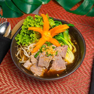 Bowl of beef noodle soup garnished with a star-shaped carrot.
