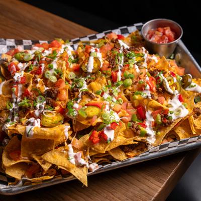 Traditional Nachos topped with tomato, jalapeno, scallions, red peppers and a sauce drizzle.