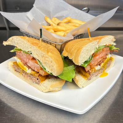 Burger patty sandwich with cheese, lettuce, and tomato, served with fries.