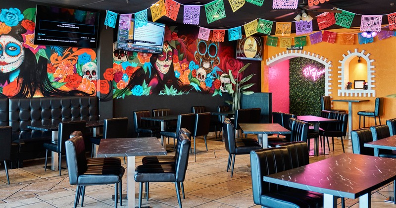 Colorful restaurant interior with Day of the Dead artwork, and black leather seating