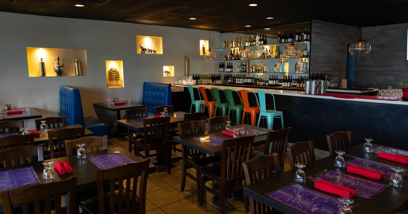 Interior of a restaurant featuring dark wooden tables, colorful bar stools