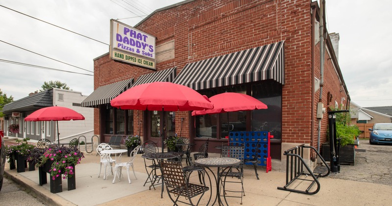 Outdoor seating area, featuring red umbrellas and flower pots in front of the restaurant