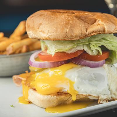 The Rooster Burger, with ham, fried egg, bacon, cheese, onion, lettuce, tomato, and fries.