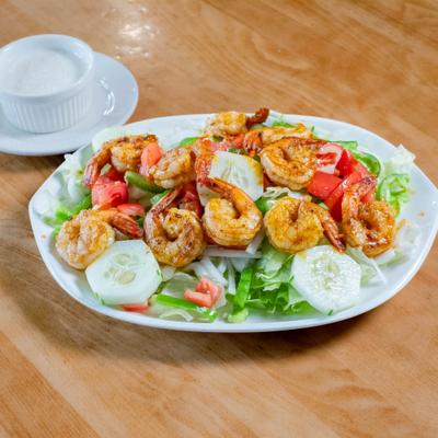 Grilled Shrimp Salad served on the table with dressing on the side.