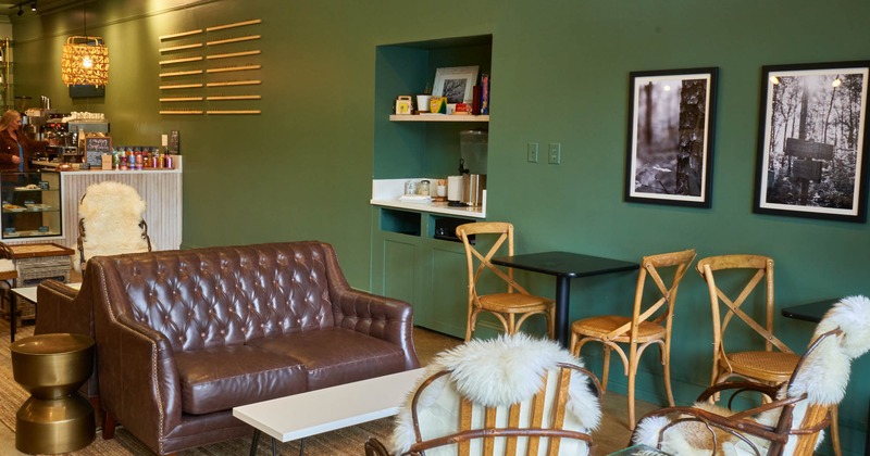 Interior, tables, chairs and brown leather sofa, framed pictures on the wall