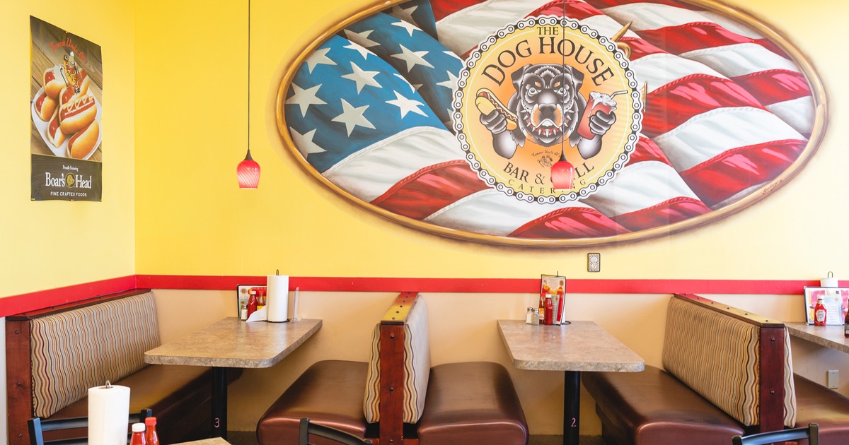 Interior space, dining tables and upholstered booth seating, restaurant logo on the wall