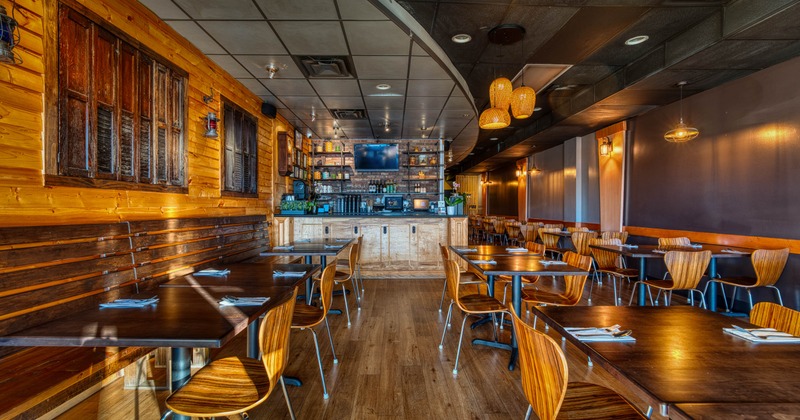 Interior of a cozy restaurant with wooden decor, tables, chairs, and a bar area
