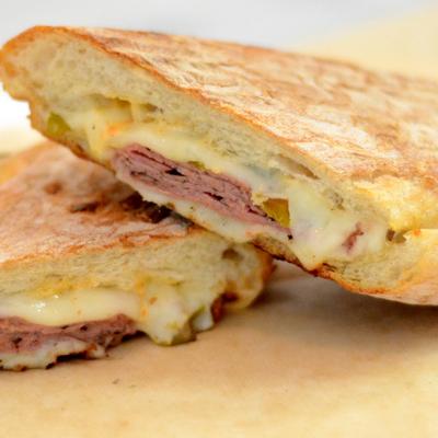 Pannini sandwich with cured meat and melted cheese, close-up.
