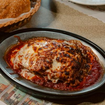 Baked lasagna with melted cheese and red sauce in an oval pan.