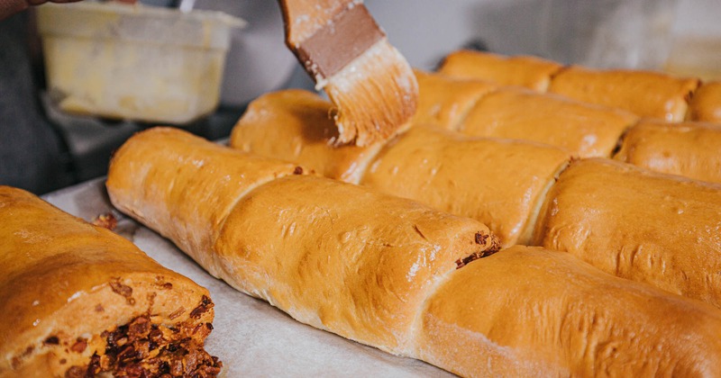A baker brushes pastry with egg wash
