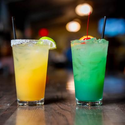 Patron Tiki Rita and Blue Mai Tai cocktails on a wooden table.