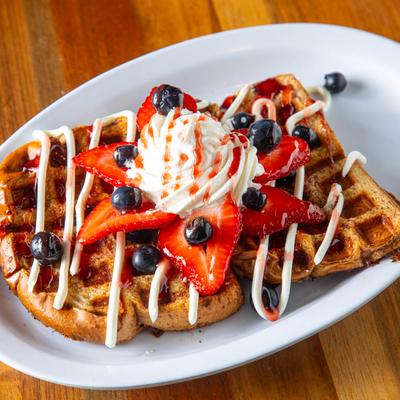 Burst of Berries French Toast topped with strawberry, blueberries, cream, and syrup.