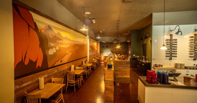 Interior, dining area, wooden top tables for two on the left, bar on the right, mural on the wall
