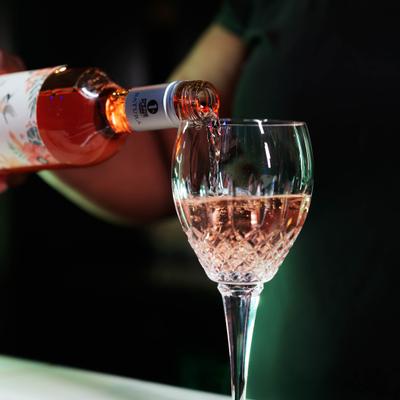 Rose wine being poured into a textured, stemmed glass.