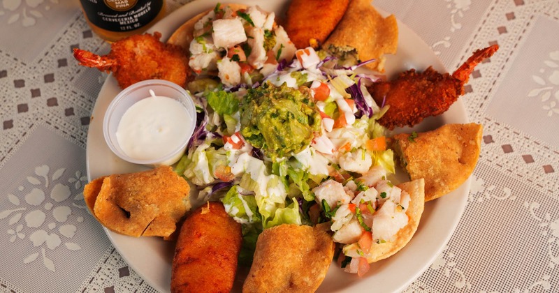 Fried seafood bites with jalapeno poppers and a salad topped with guacamole