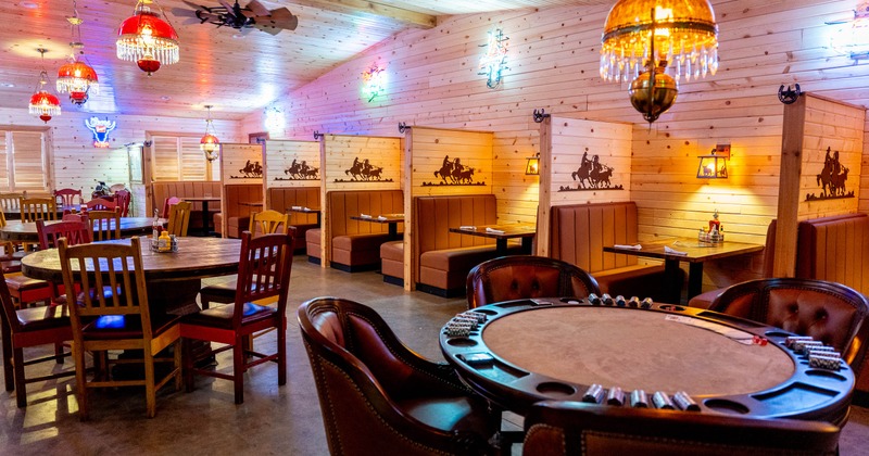 Rustic restaurant interior with wooden booths, poker table, and stained glass lamps