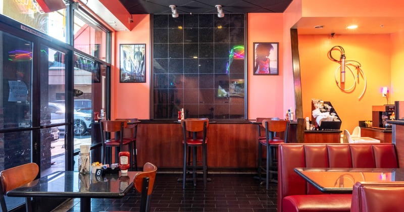 Interior - orange walls, black tiled section, red seating, large window and framed pictures