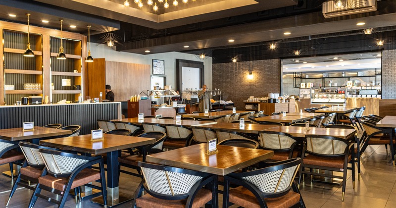 Interior seating area with wooden tables and wicker-backed chairs