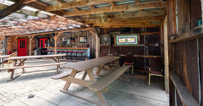 Exterior, covered seating area, wooden tables with benches, bar with stools in the back