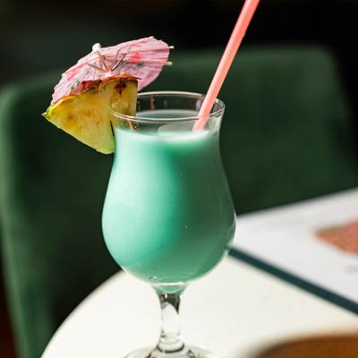 Blue Hawaiian cocktaul, garnished with a slice of pineapple and a umbrella.