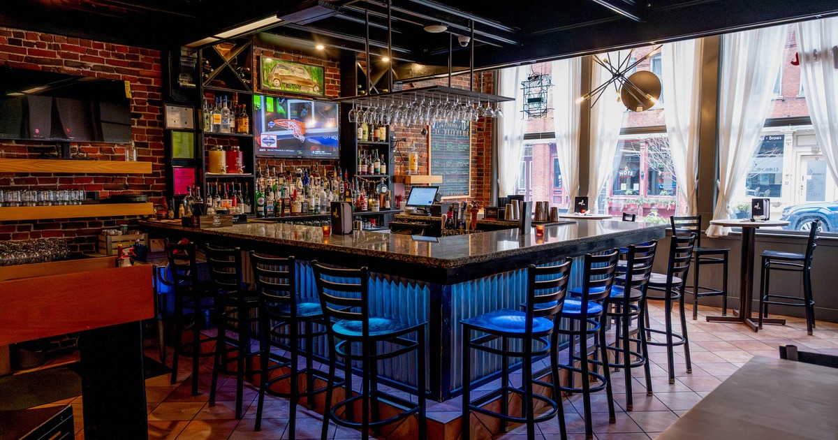 Interior, bar area, marble top bar with stools, checkout counter, drink shelves in the back