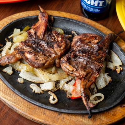 Grilled quail served on a hot sizzling platter over grilled onions.