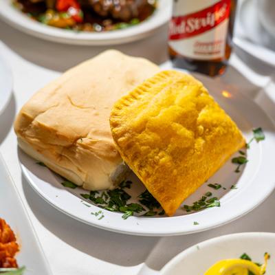 Jamaican beef patty served on the plate alongside cornbread.