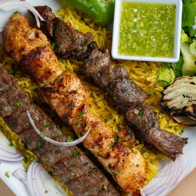 Beef, chicken and ground meat kebabs served over yellow rice with green dipping sauce.