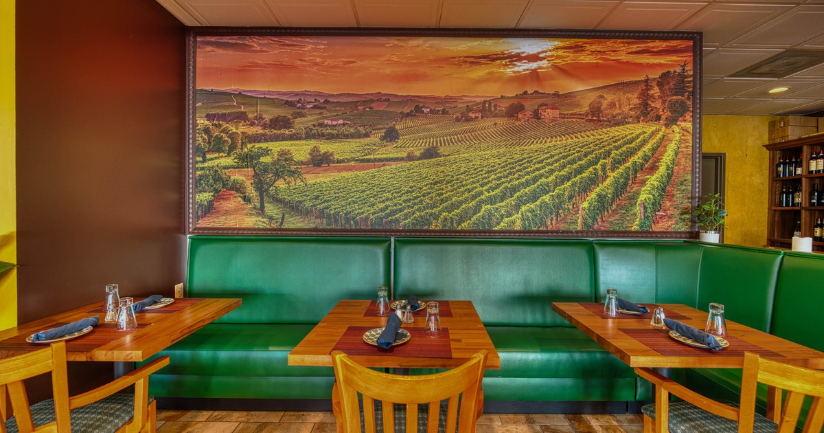 Interior - a vineyard mural, green seating, wooden tables set with glasses and napkins.