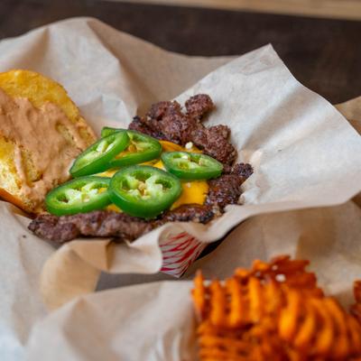 A cheeseburger with jalapenos and waffle fries.