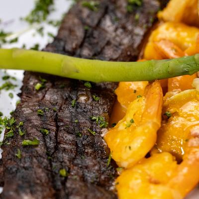 Close-up view of a skirt steak with jumbo shrimp.