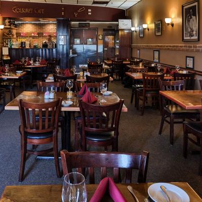 Dining room with set tables, framed art on the wall and bar counter.