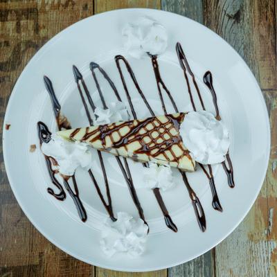 Overhead view of a cheesecake slice topped with whipped cream and chocolate drizzle.
