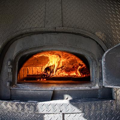 Wood-fired pizza oven with visible flames.