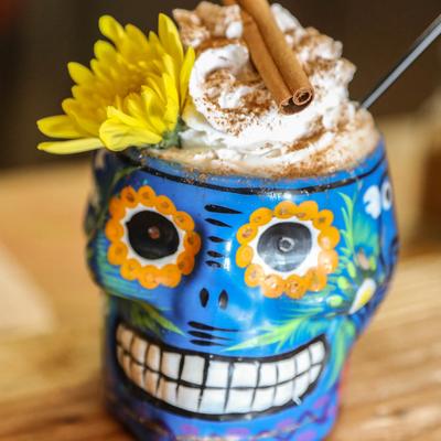 Mexican-style hot chocolate in a sugar skull, topped with whipped cream and cinnamon.