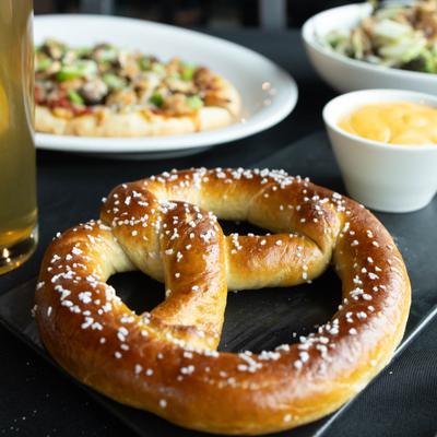Pretzel served with  beer cheese dip and a glass of beer.