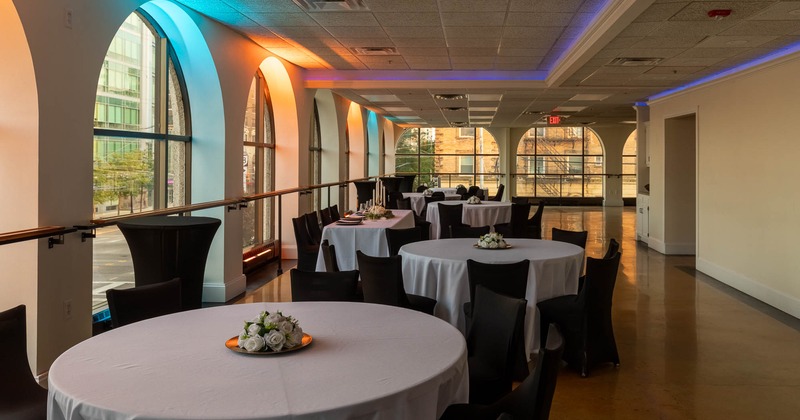 Interior, round tables, white cloth tables with flower centerpieces, arched windows