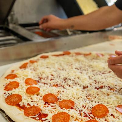 Chef preparing a pepperoni and cheese pizza.
