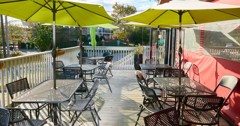 Exterior, patio, metal tables and chairs under parasols, railing, entrance