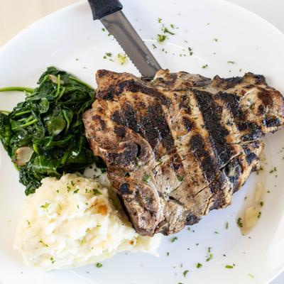 Roman-style veal cutlets served with mashed potato over spinach in a sauce.