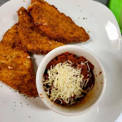 Fried fish fillets with a side of chili topped with shredded cheese.