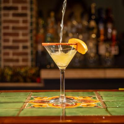 Margarita being strained into a chilly-rimmed glas with citrus garnish.