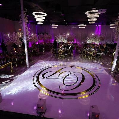Elegant event space with purple lighting, floral centerpieces, and a glossy dance floor.