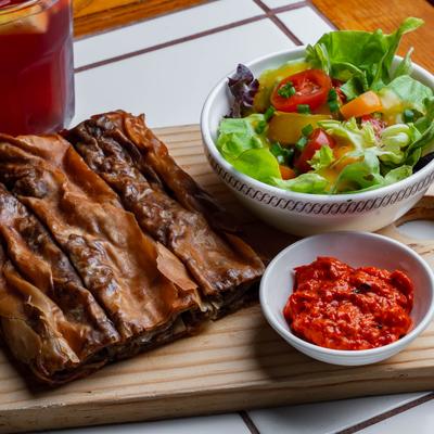 Beef burek served with house salad and pepper and eggplant condiment on the side.