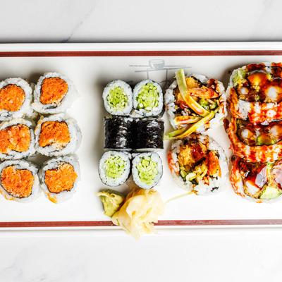 A plate of sushi with rolls of various types garnished with ginger and wasabi.