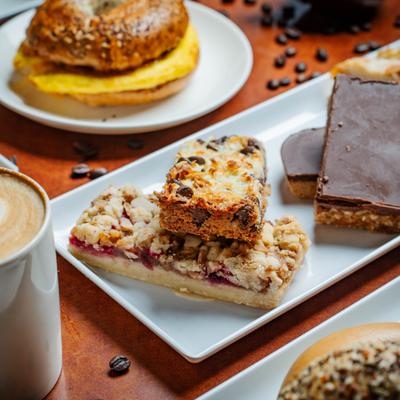 Several types of bars served alongside breakfast bagel and a cup of coffee.